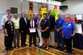 Lions club members with Community and YMCA members in front of Jumping Castle