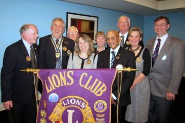 Women and men standing behind a lions club banner